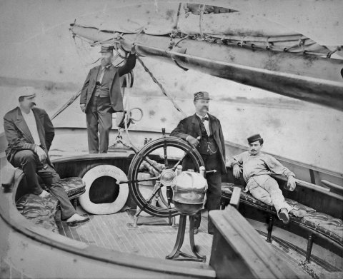 Photograph of Andrew Jackson Comstock at the wheel of the racing schooner, Columbia, circa 1880.